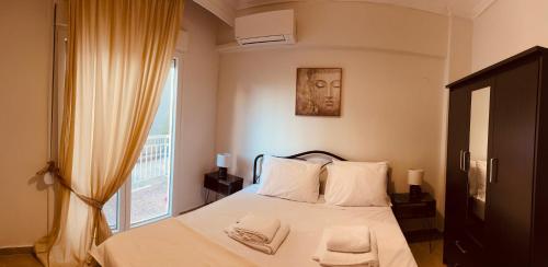 a bedroom with a bed with white sheets and a window at Blue two apartment in Kavála