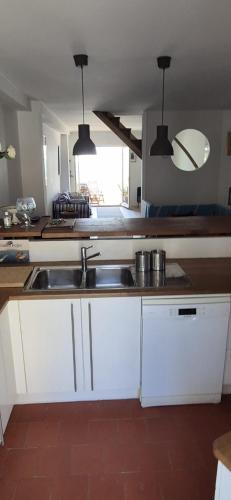 une cuisine avec des armoires blanches et un évier dans l'établissement La maison bleue, à Bouzigues