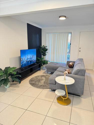 a living room with a couch and a tv at Serenity Stay Brisbane in North Lakes