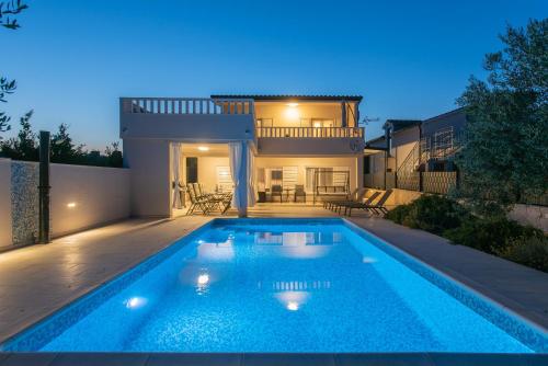 a swimming pool in front of a house at Beachfront villa Mihovil with direct beach access in Kastel Stafilic