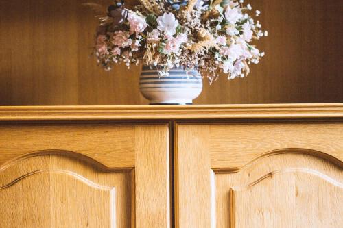 a vase of flowers on top of a wooden cabinet at Pension Neururer in Sölden