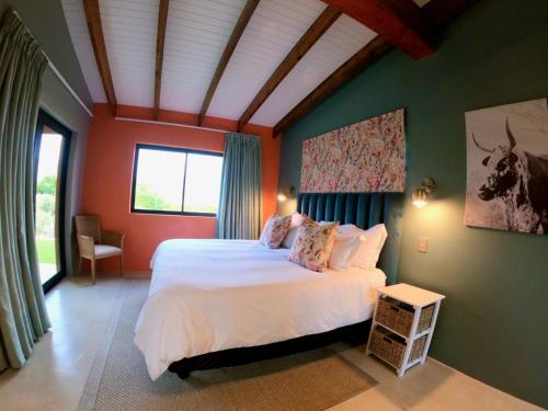 une chambre avec un grand lit blanc dans une pièce dans l'établissement AlteVrede Olive Farm, à Doornrivier