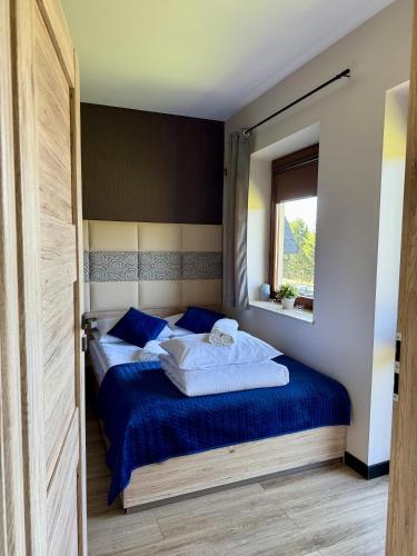 a bedroom with a bed with blue sheets and a window at Błękitne Wierchy in Murzasichle