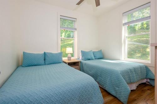 two blue beds in a room with two windows at Unwind at Lakey McLakehouse on Lake Santeetlah in Robbinsville