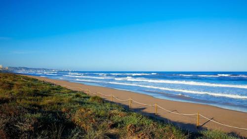 a fence on a beach with the ocean at Cozy Beachside Apartment in Tavernes de Valldigna