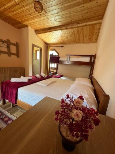 a bedroom with a bed and a table with flowers on it at Guest House Shtëpiza Theth in Theth