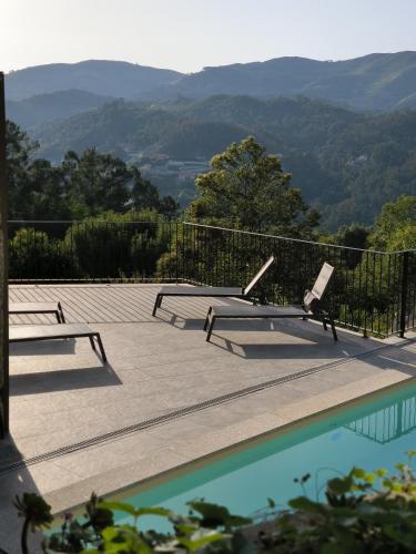 a pool with two benches and a view of mountains at QG Quinta de Grovelas in Balança