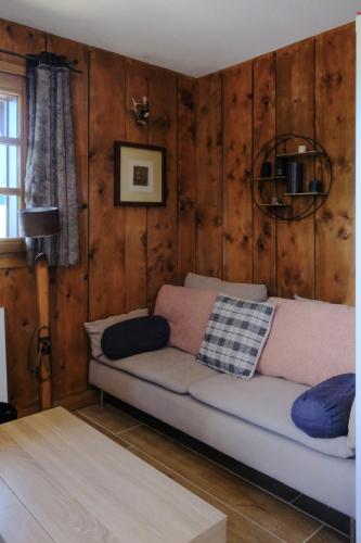 - un canapé dans le salon doté de murs en bois dans l'établissement Ali'Home vue MontBlanc - T2 de charme, à Demi-Quartier