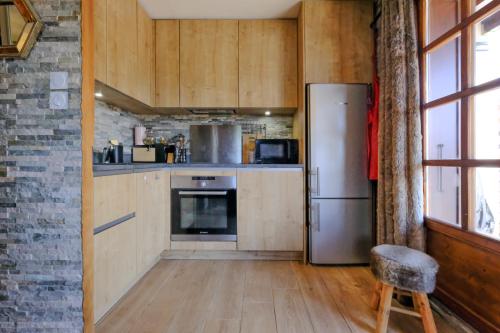 Il comprend une cuisine équipée d'un réfrigérateur et d'une chaise. dans l'établissement Ali'Home vue MontBlanc - T2 de charme, à Demi-Quartier