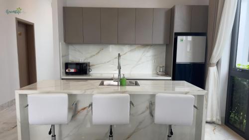 a kitchen with a sink and four white chairs at Greenlife Village Phú Quốc in Phu Quoc