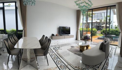 a living room with a table and chairs and a tv at Greenlife Village Phú Quốc in Phu Quoc