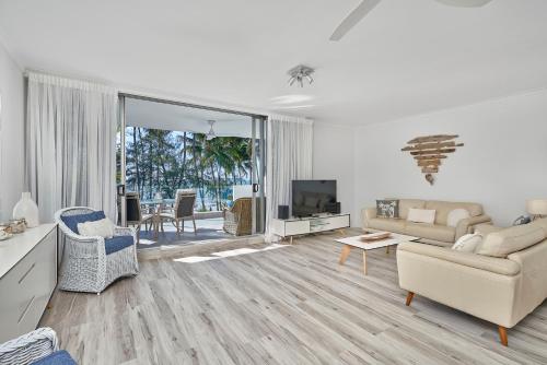 パーム・コーブにあるParinga Beachfront Apartment 7 with Ocean Viewsのソファとテレビのあるリビングルーム
