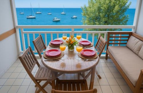 a table with plates and glasses on a balcony at Vacances pieds dans l'eau in Les Trois-Îlets