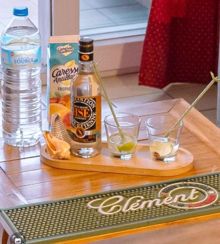 a bottle of alcohol and two glasses on a table at Vacances pieds dans l'eau in Les Trois-Îlets