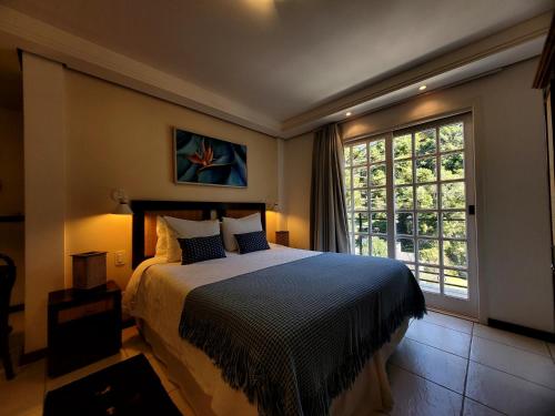 a bedroom with a bed and a large window at Pousada Cheverny - Fácil acesso ao centrinho e Baden Bar in Campos do Jordão