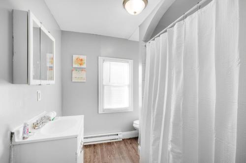 a bathroom with a white shower curtain and a sink at Bright Corner Flat Near Transit And Trails in Philadelphia