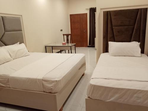 a bedroom with two beds and a table in it at Dove INN Express in Lahore