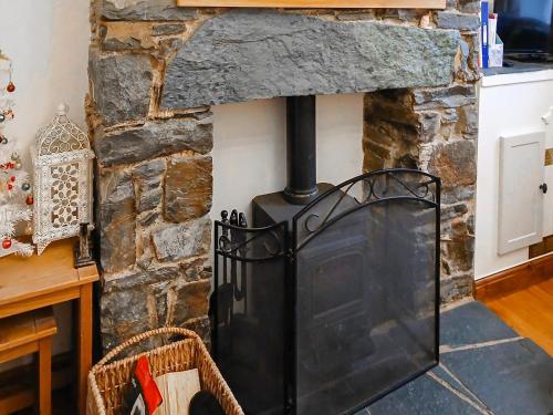 een stenen open haard met een zwarte kachel bij 1 Tower Cottage in Portinscale