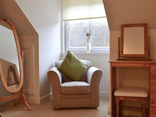 a bathroom with a chair and a mirror at Riverside in Kilmelfort