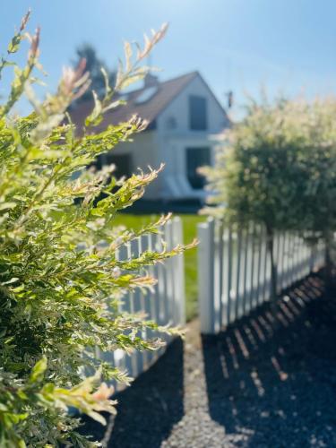 a white picket fence in front of a house at Dom wakacyjny z podgrzewanym basenem w tarasie i jacuzzi pod gwiazdami, Studnica, Ińsko, "THerapeutica" 