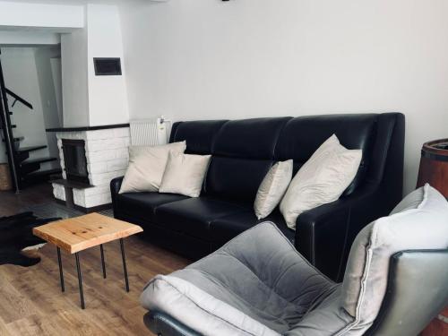 a living room with a black couch and a table at Dom wakacyjny z podgrzewanym basenem w tarasie i jacuzzi pod gwiazdami, Studnica, Ińsko, "THerapeutica" 