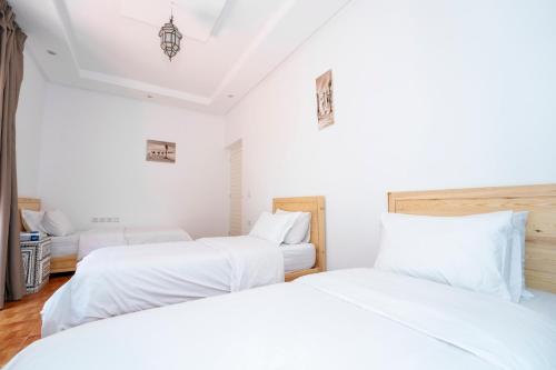 two beds in a room with white sheets at Chalet berbère 2 Chambres avec Piscine &Wifi fibre in Essaouira