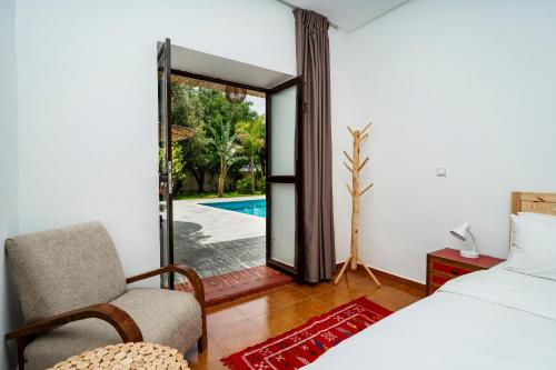 a bedroom with a bed and a chair and a pool at Chalet berbère 2 Chambres avec Piscine &Wifi fibre in Essaouira
