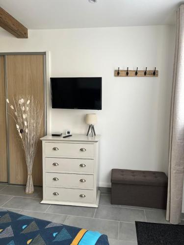 a white dresser with a television on a wall at Logement avec jardin à Sotteville-sur-Mer in Sotteville-sur-Mer
