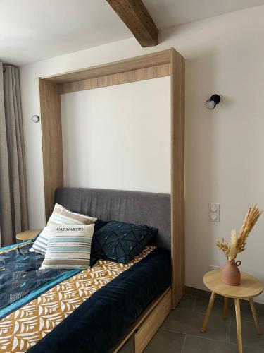 a bedroom with a bed with a wooden headboard and a table at Logement avec jardin à Sotteville-sur-Mer in Sotteville-sur-Mer