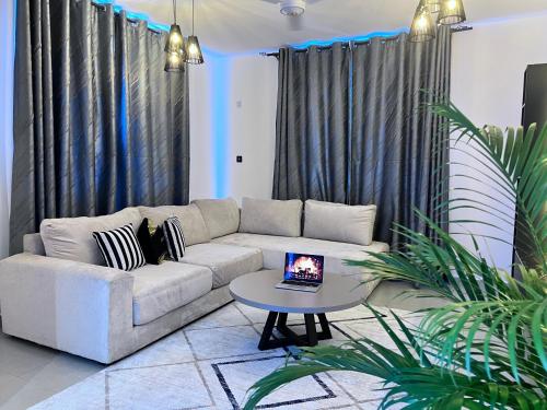 a living room with a couch and a table with a laptop on it at Deanway homes,2bedroom Apartment Vale Residence Nyali in Mombasa