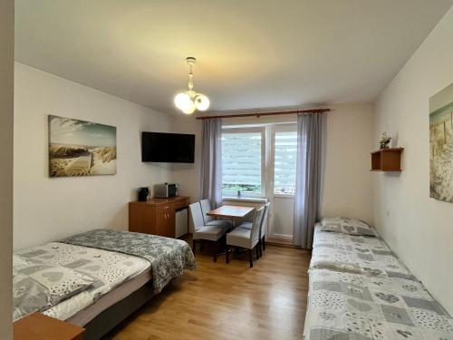 a bedroom with two beds and a desk and a window at Pokoje Gościnne U RYBAKA in Karwia