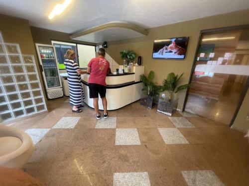a man and a woman standing at a counter at Pousada Maré Alta em Pajuçara in Maceió