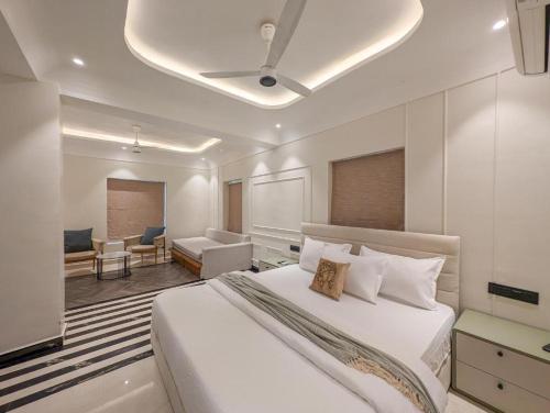 a bedroom with a large white bed and a living room at Villa Candolim in Candolim