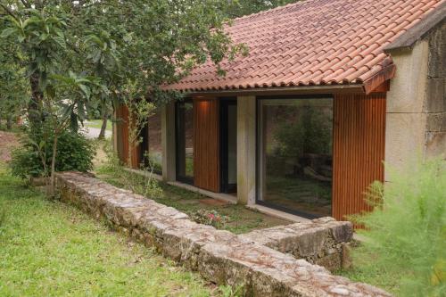 a house with glass windows and a stone wall at Quinta da Fenteira - Casa Tora in Arcos de Valdevez