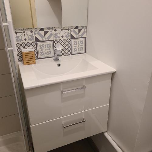 La salle de bains est pourvue d'un lavabo blanc et de carrelage sur le mur. dans l'établissement Appartement Brest Saint Martin avec belles prestations, à Brest