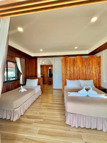 two beds in a room with wooden floors at Pen's Bungalow Koh Phangan in Thong Nai Pan Yai