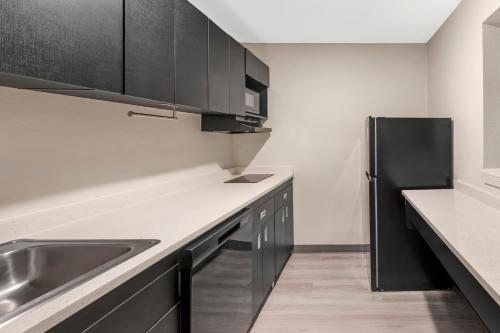 a kitchen with a sink and a black refrigerator at MainStay Suites Little Rock West Near Medical Centers in Little Rock