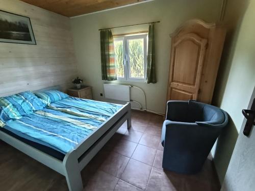 a bedroom with a bed and a chair at Domki Helena Okuninka in Okuninka
