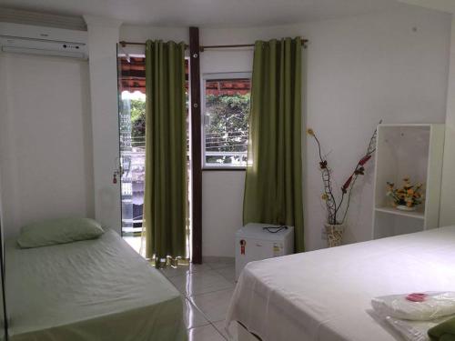 um quarto com 2 camas e uma janela com cortinas verdes em pousada do rei em Pedra de Guaratiba