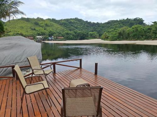 ein Holzdeck mit Stühlen auf einem Gewässer in der Unterkunft Casa na Barra do Una, à beira do Rio Una e frente a Praia in São Sebastião