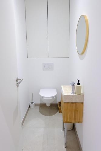 a white bathroom with a toilet and a mirror at Bordeaux Village Blaye in Blaye
