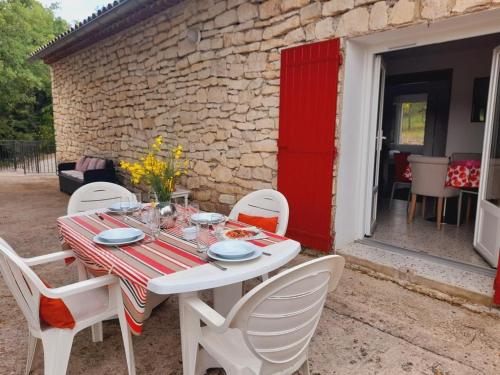une table blanche avec des chaises blanches et une porte rouge dans l'établissement GITE des VERGIERS, à Murs