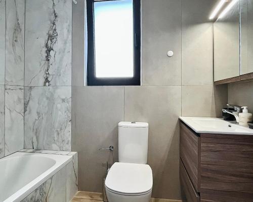 Un baño con inodoro, bañera y lavabo. en Villa Greige, en Ixia