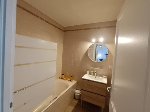 une salle de bain avec une baignoire, un lavabo et un miroir dans l'établissement le contemporain, à Bastia