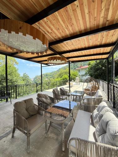 a patio with chairs and tables and a wooden ceiling at Kvariati House in Kvariati