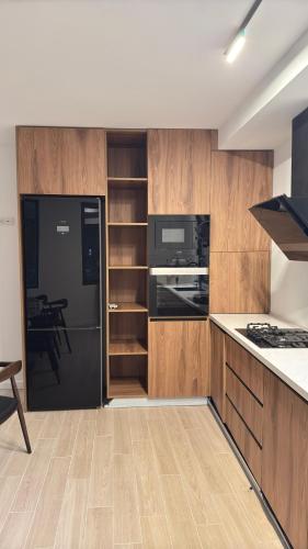 a kitchen with a black refrigerator and wooden cabinets at Kvariati House in Kvariati