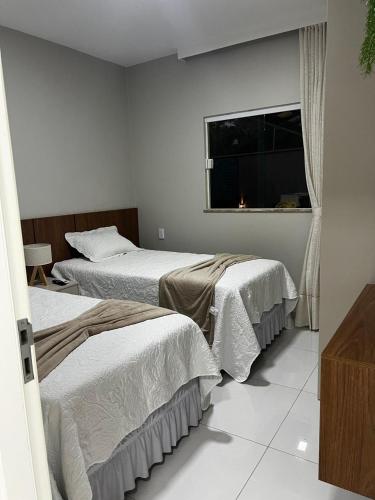 two beds in a room with a window at Casa Caju Lençóis in Barreirinhas