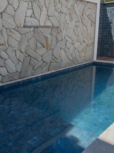 a swimming pool with a stone wall next to a rock wall at Casa Caju Lençóis in Barreirinhas