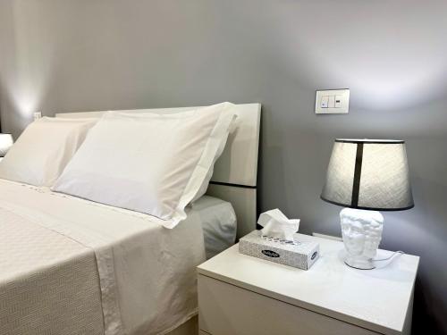 a white bed with a lamp on a night stand at Petranera Apartment in Randazzo