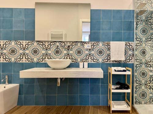 a blue tiled bathroom with a sink and a mirror at Petranera Apartment in Randazzo
